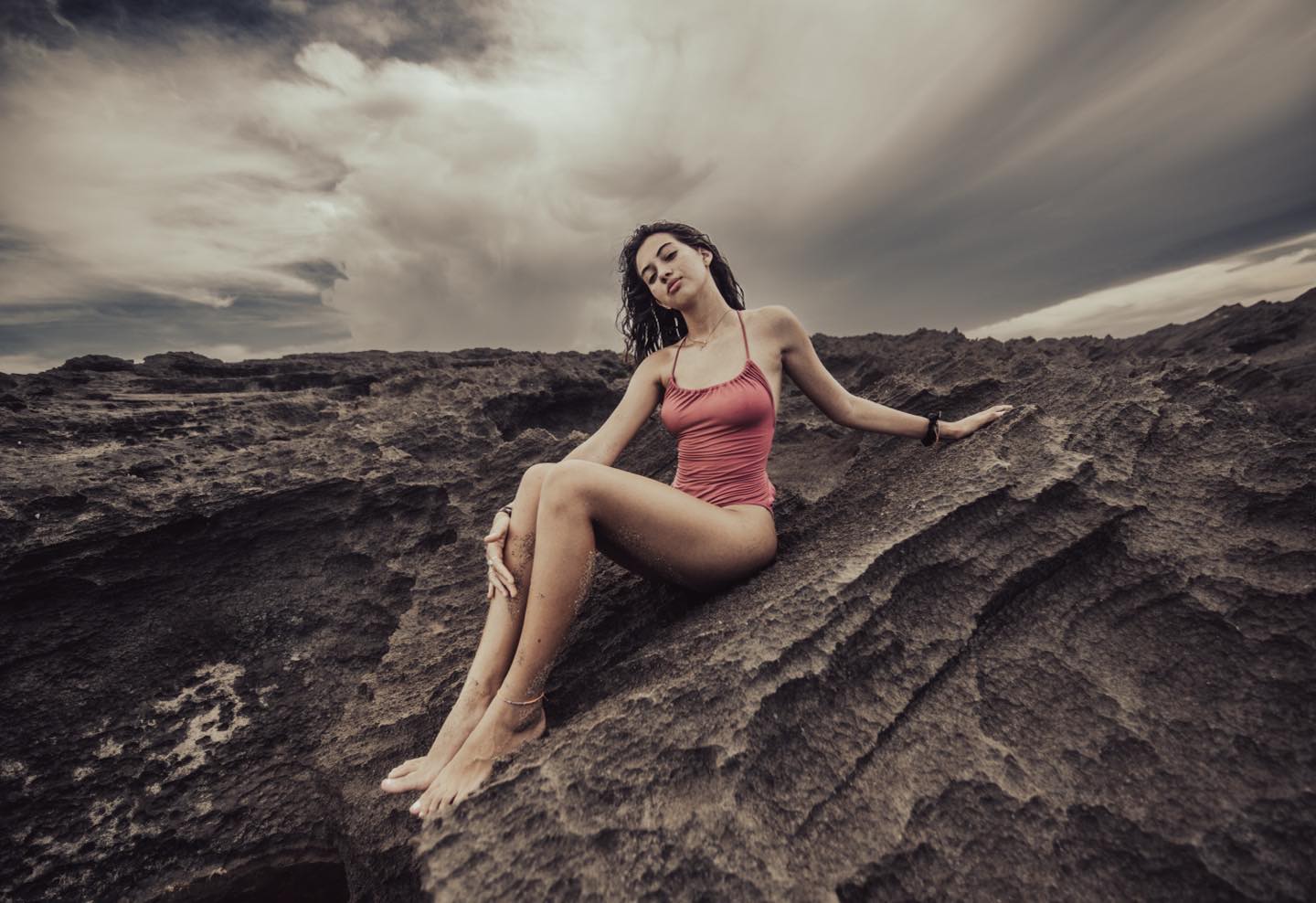 Outdoor portrait of a woman on a rocky landscape under cloudy skies